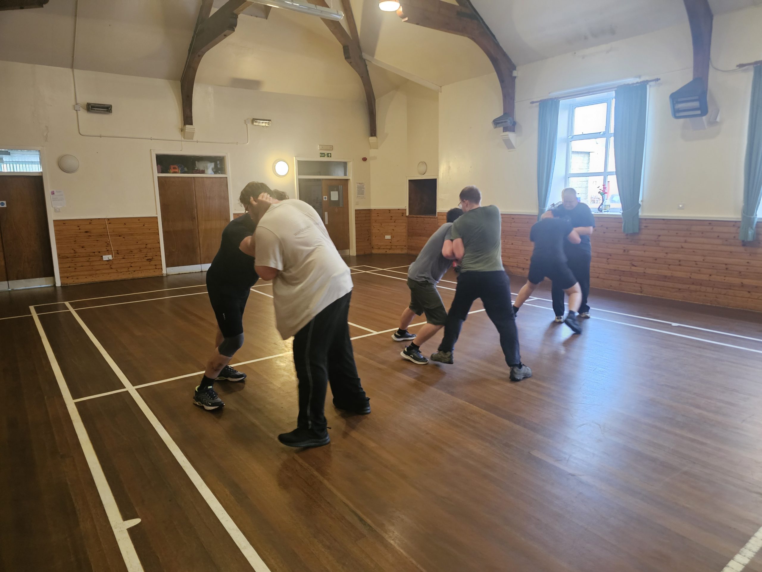 Pairs of people grappling in community sports hall
